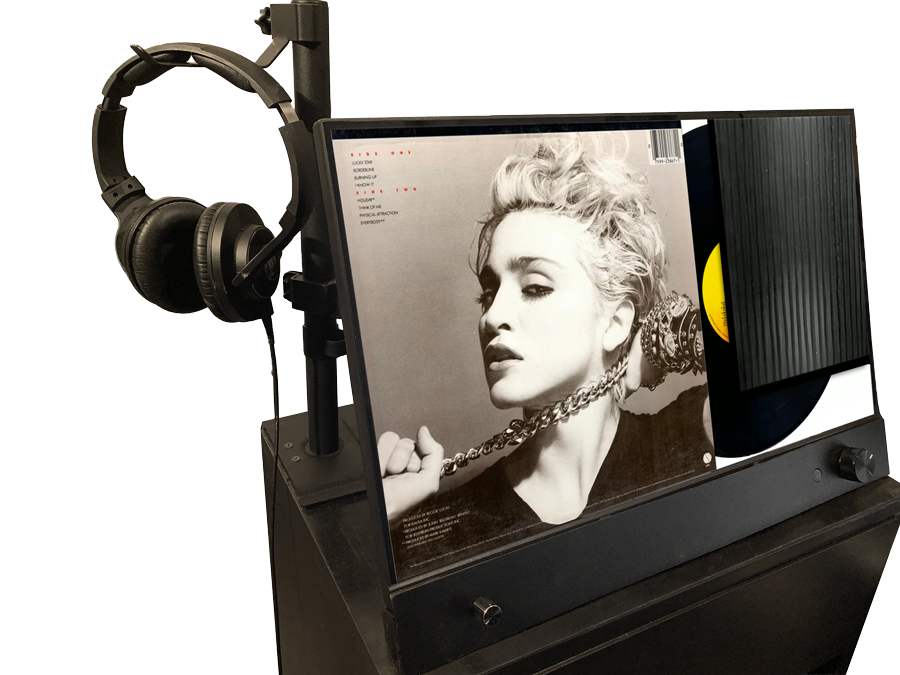 Headphones mounted on a gooseneck stand beside the Almont display's touchscreen, ready for customers to use as a listening station.
